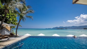 Una piscina al aire libre, sombrillas, sillones reclinables de piscina