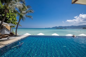A clear blue pool with a view of the ocean and mountains, surrounded by palm trees and umbrellas. - Baan Haad Ngam Boutique Resort & Villas (Koh Samui)