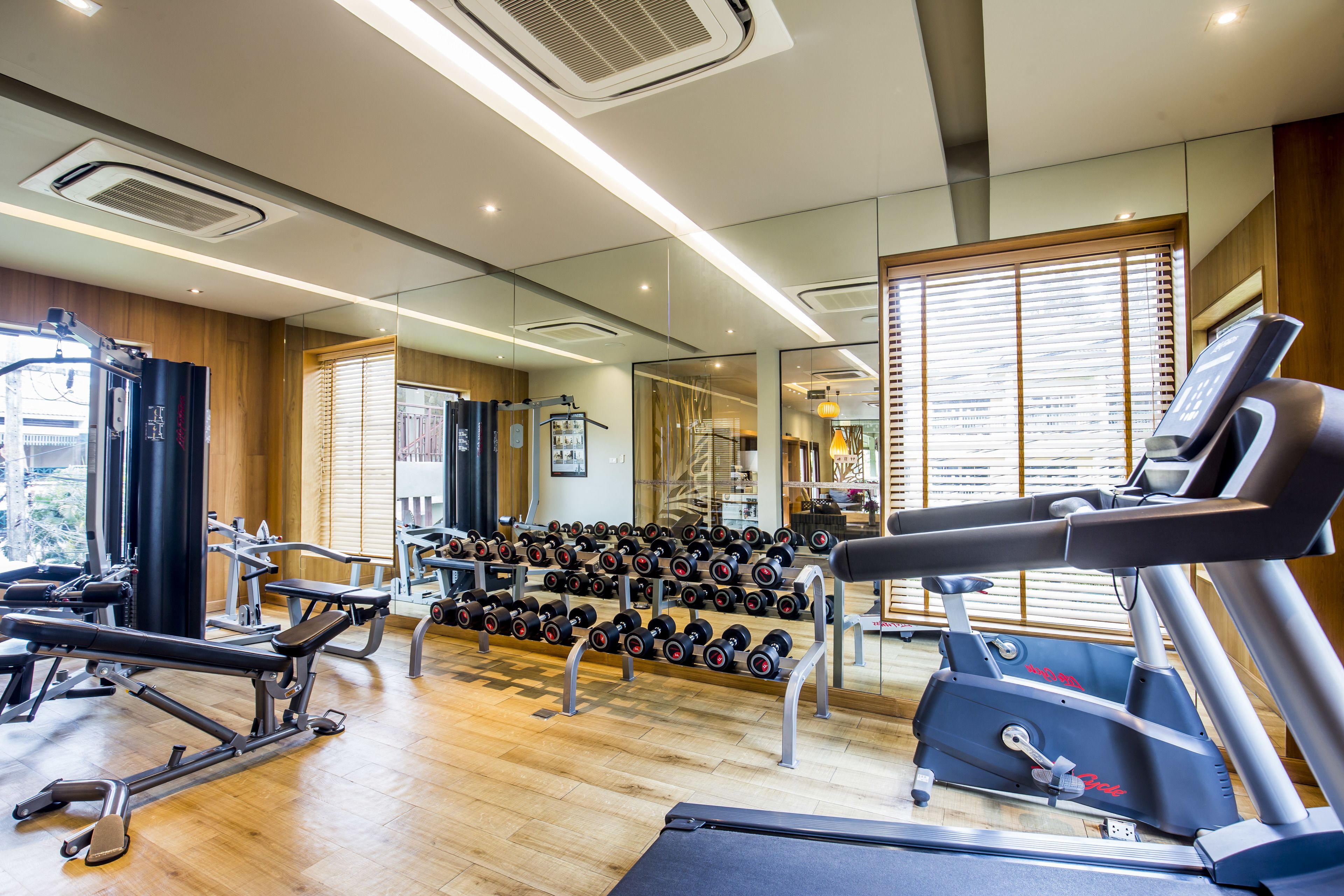 Een moderne sportschool met trainingsapparatuur, een loopband en een spiegel die de ruimte weerspiegelt.