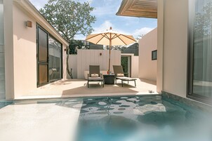 Area piscina moderna all'aperto con una sdraio e un ombrellone, immersa in un design architettonico minimalista.
