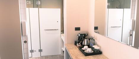 A modern kitchen with a marble countertop, a coffee machine, and a small seating area.