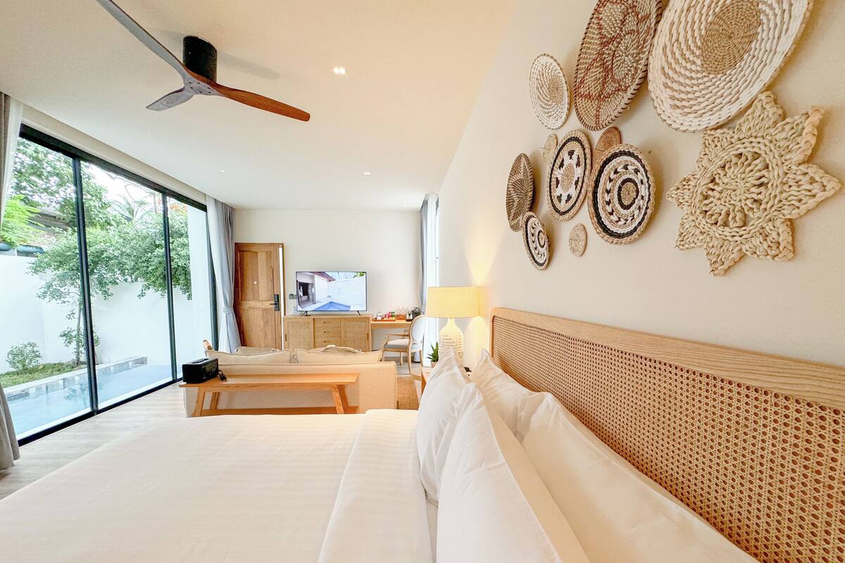 A spacious bedroom with a large bed, a desk, and a television.