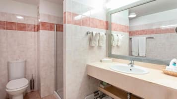 Ein Badezimmer mit Toilette, Waschbecken, Dusche und Spiegel.