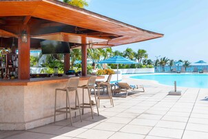 Una piscina al aire libre, sombrillas, sillones reclinables de piscina