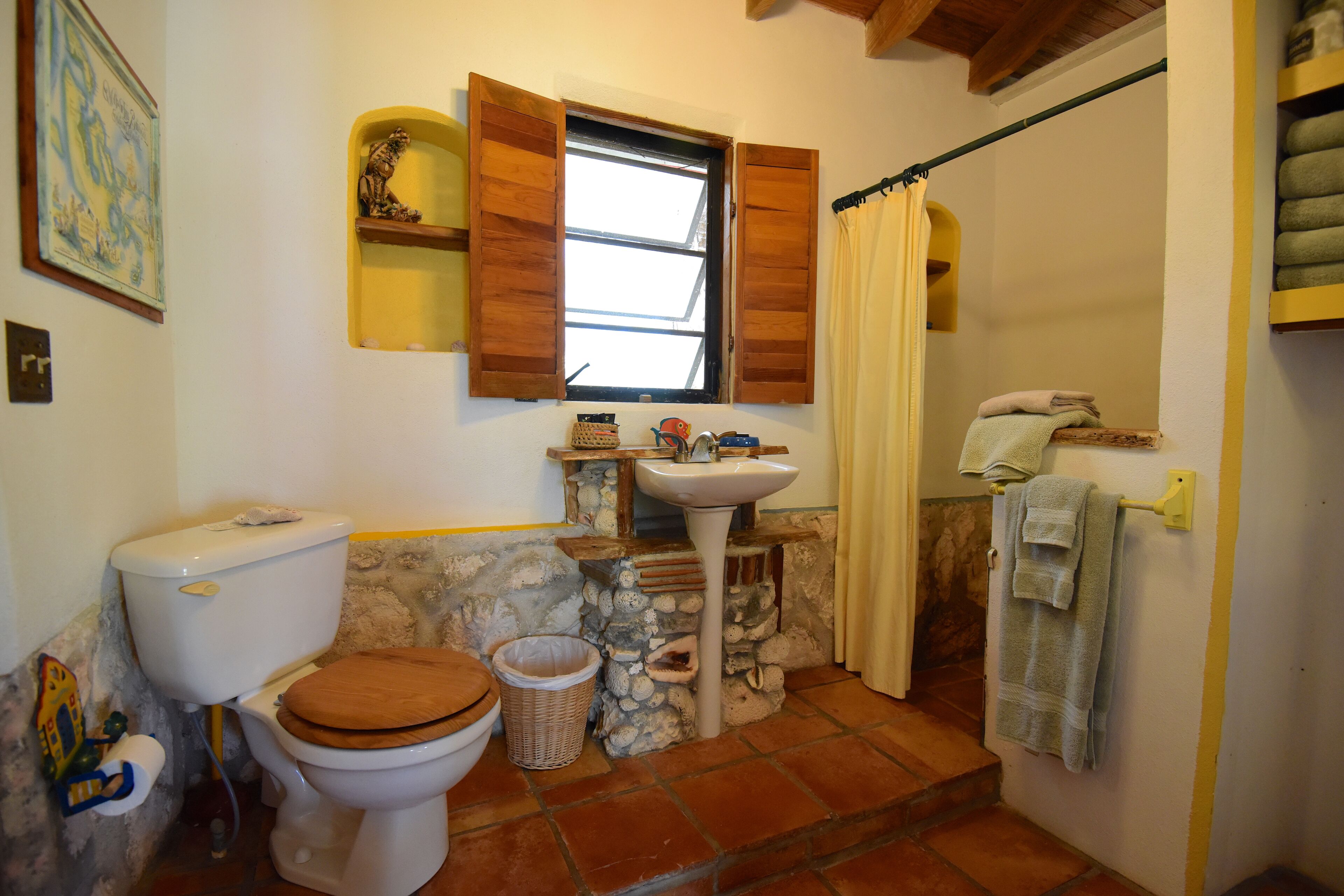 A bathroom with a toilet, sink, and window with wooden shutters.