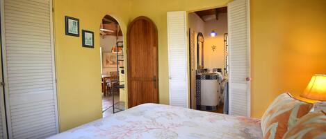 A bedroom with a bed, wooden door, and a mirror.