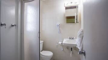 A bathroom with a toilet, sink, and shower.