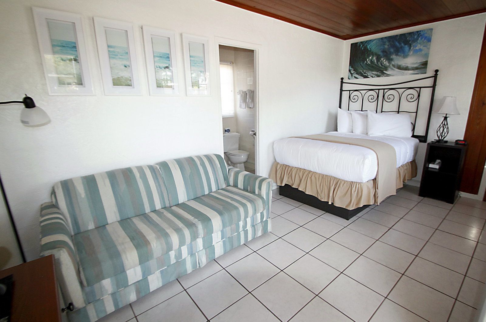 Un dormitorio con cama, sofá y baño a la vista a través de una puerta abierta.