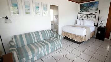 Un dormitorio con cama, sofá y baño a la vista a través de una puerta abierta.