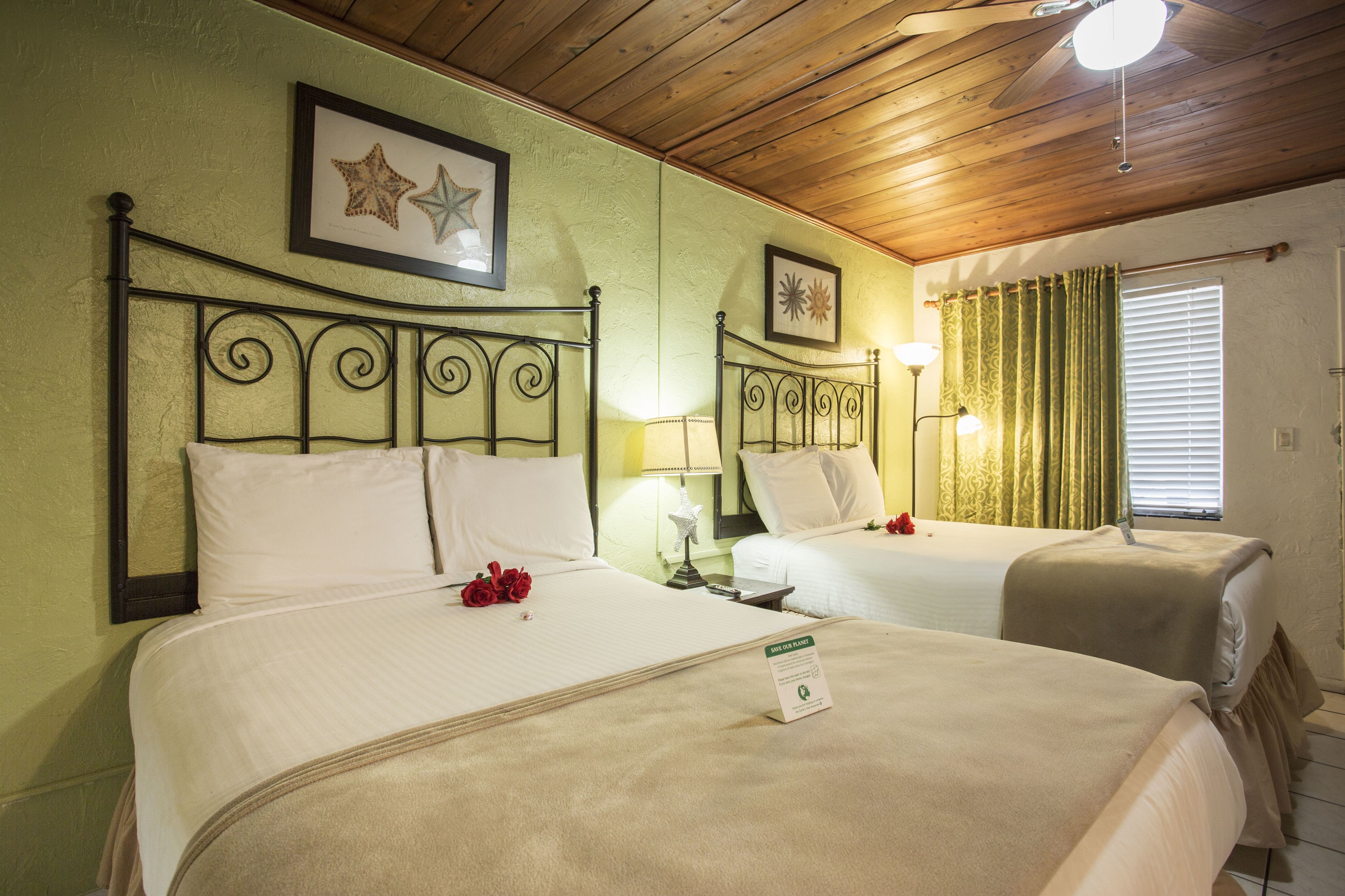 Habitación de hotel con dos camas, techo de madera y un cuadro enmarcado en la pared.