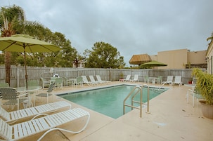 Una piscina al aire libre, sombrillas, sillones reclinables de piscina