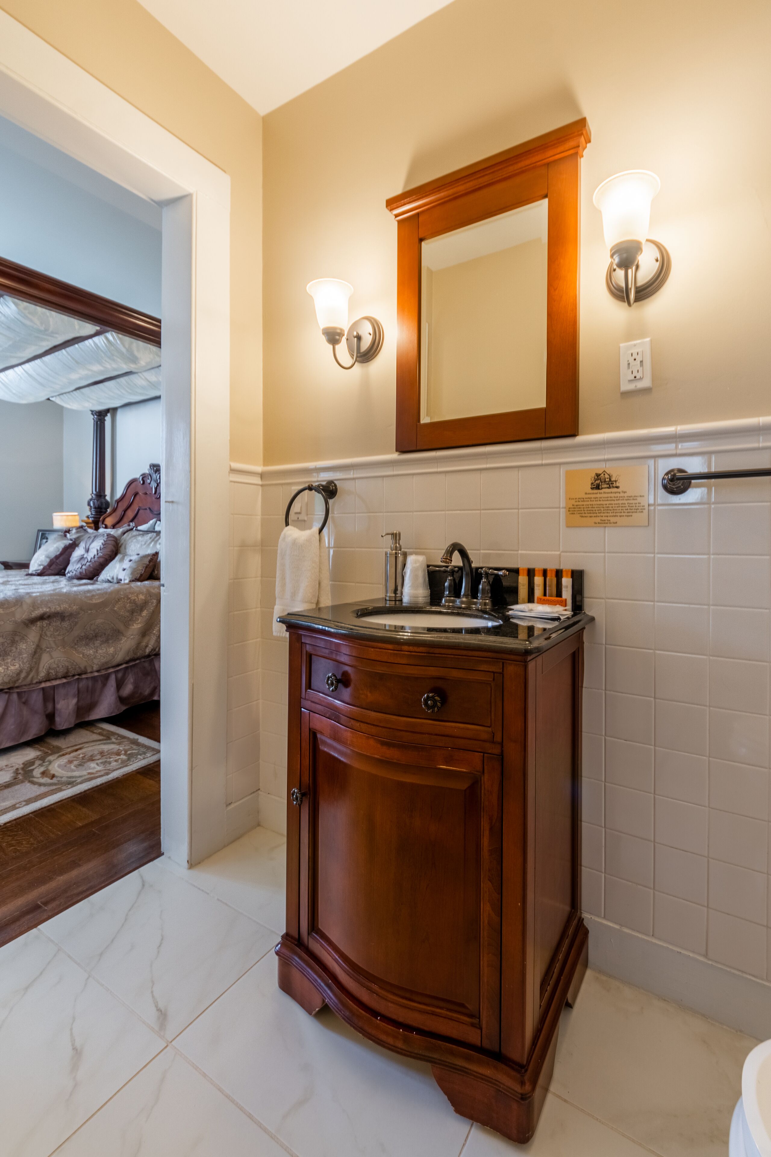 Un baño con tocador de madera, espejo y dos luces de pared.