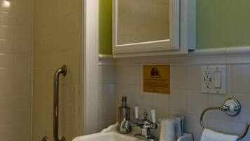 A bathroom with a shower, grab bars, a sink, and a mirror.