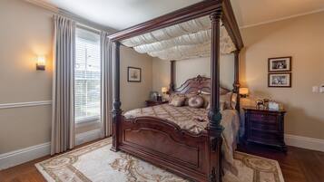 A four-poster bed with a canopy, a nightstand with a lamp, and a framed picture on the wall.