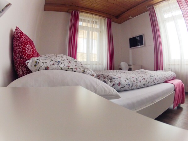Un dormitorio con una cama, un escritorio y un televisor.