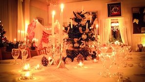 Un comedor cálidamente iluminado con un árbol de Navidad, velas y una araña.