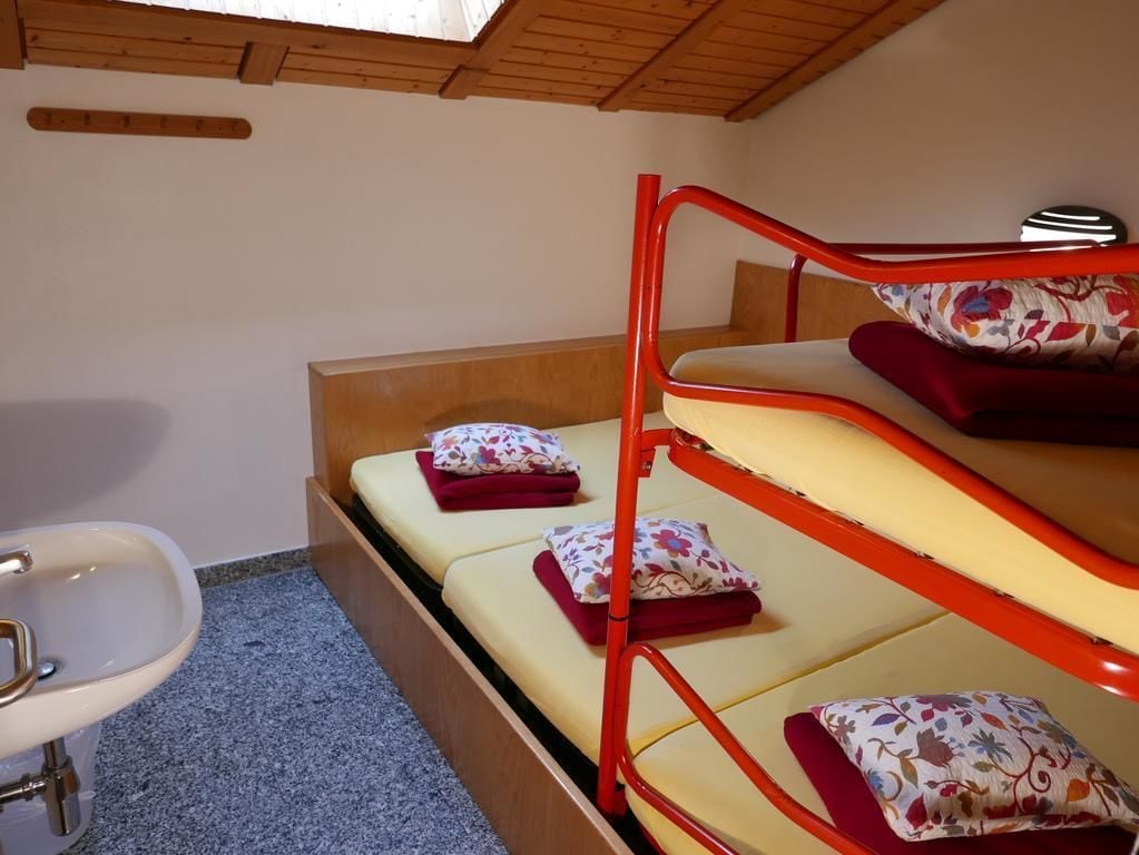 Ein Stockbett mit blumigem Kissenmuster, einem Holz-Kopfstück und einem weißen Waschbecken.