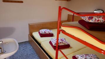 Ein Stockbett mit blumigem Kissenmuster, einem Holz-Kopfstück und einem weißen Waschbecken.