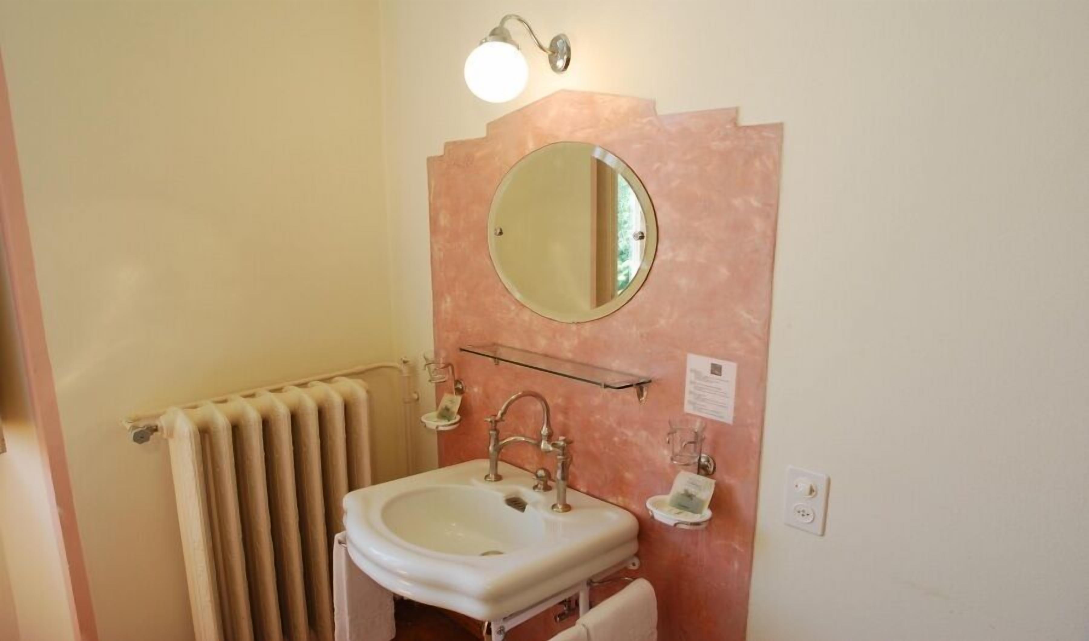 Un baño con lavamanos blanco, espejo, toallero e iluminación.
