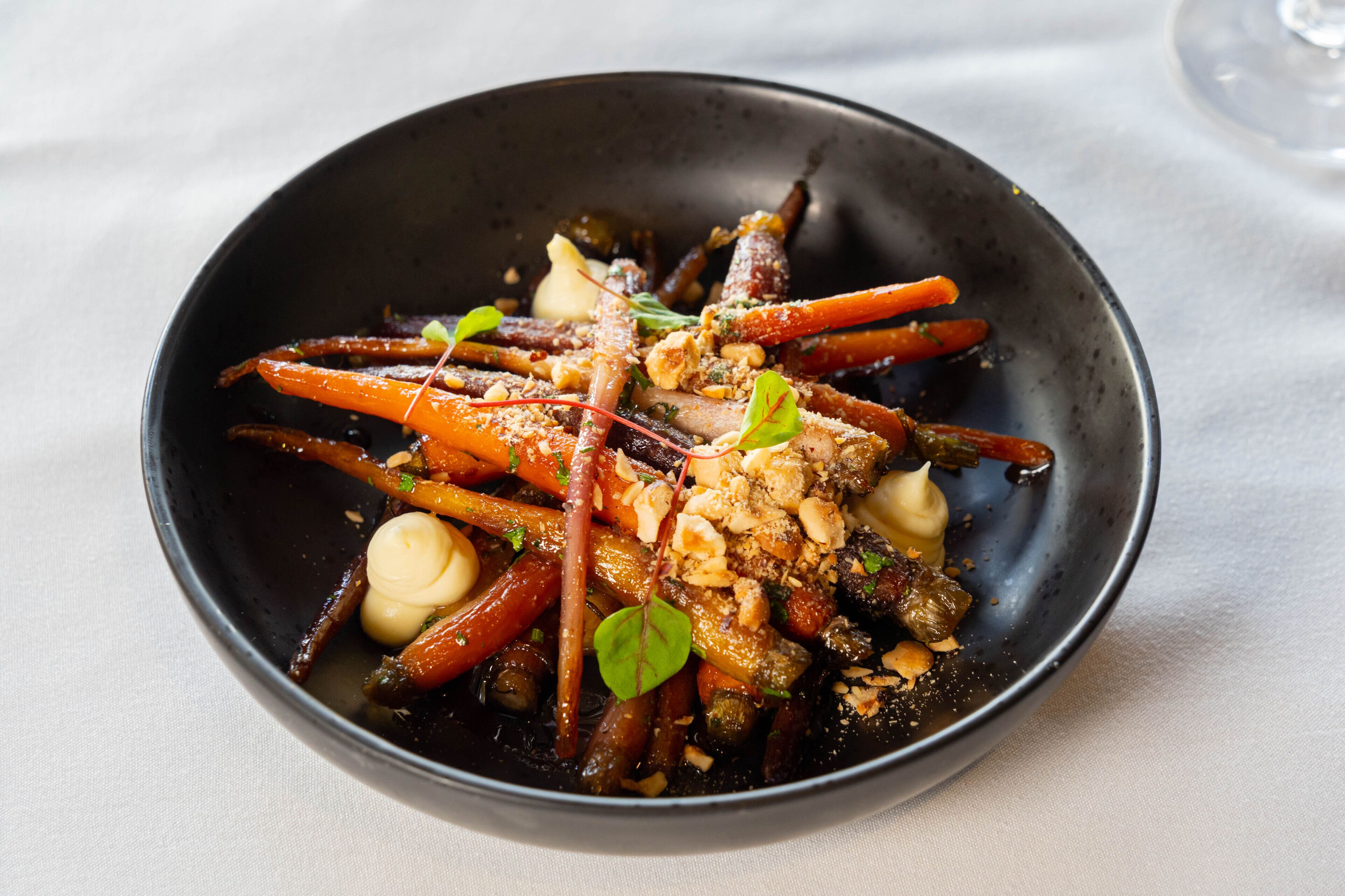 A bowl of food with various vegetables and nuts.