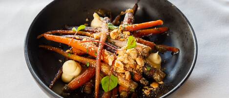 A bowl of food with various vegetables and nuts.