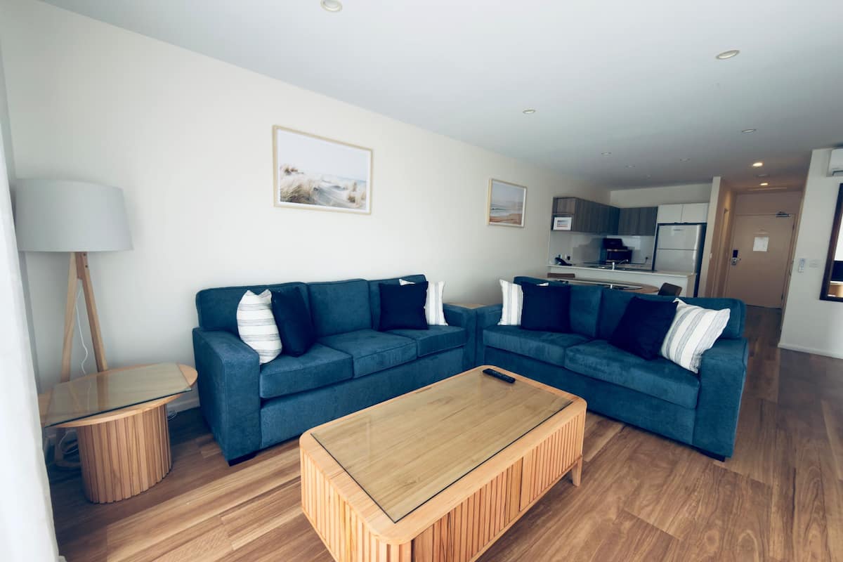 Een moderne woonkamer met een hoekbank, een salontafel en een lamp.
