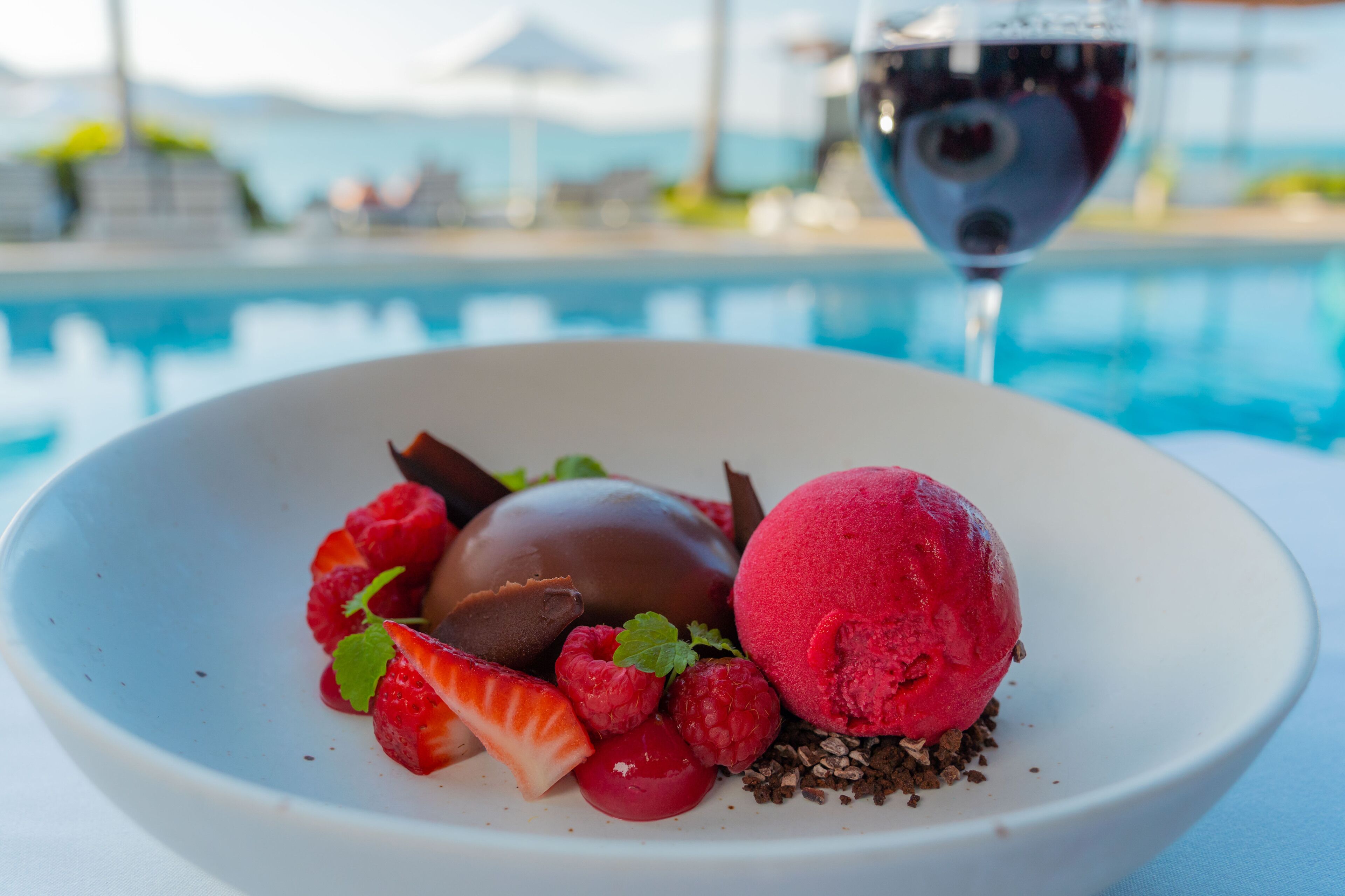 A dessert with strawberries, chocolate, and a scoop of ice cream on a white plate.
