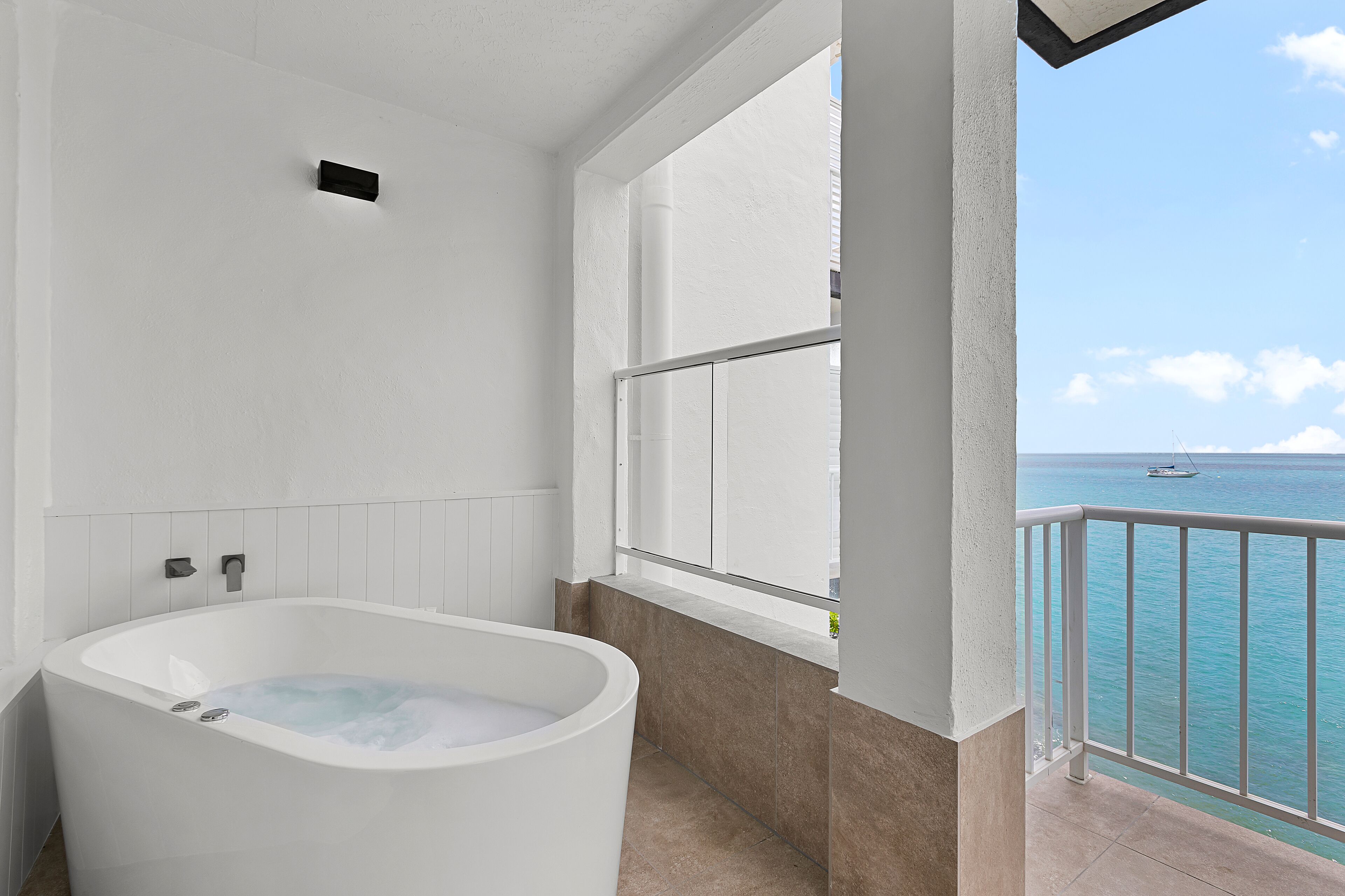 Un baño con bañera, ventana y vistas al mar.
