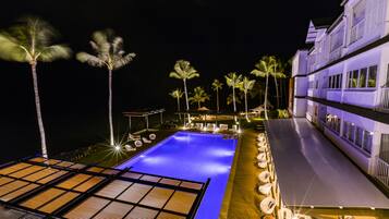 Relax by the pool surrounded by palm trees and lounge chairs.