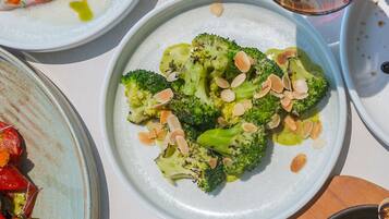 A table with various dishes including broccoli, a glass of red wine, and other food items.