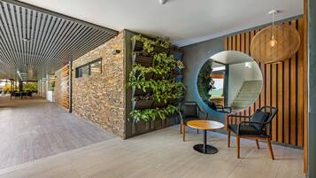 A modern interior with a stone wall, vertical garden, and a round mirror.