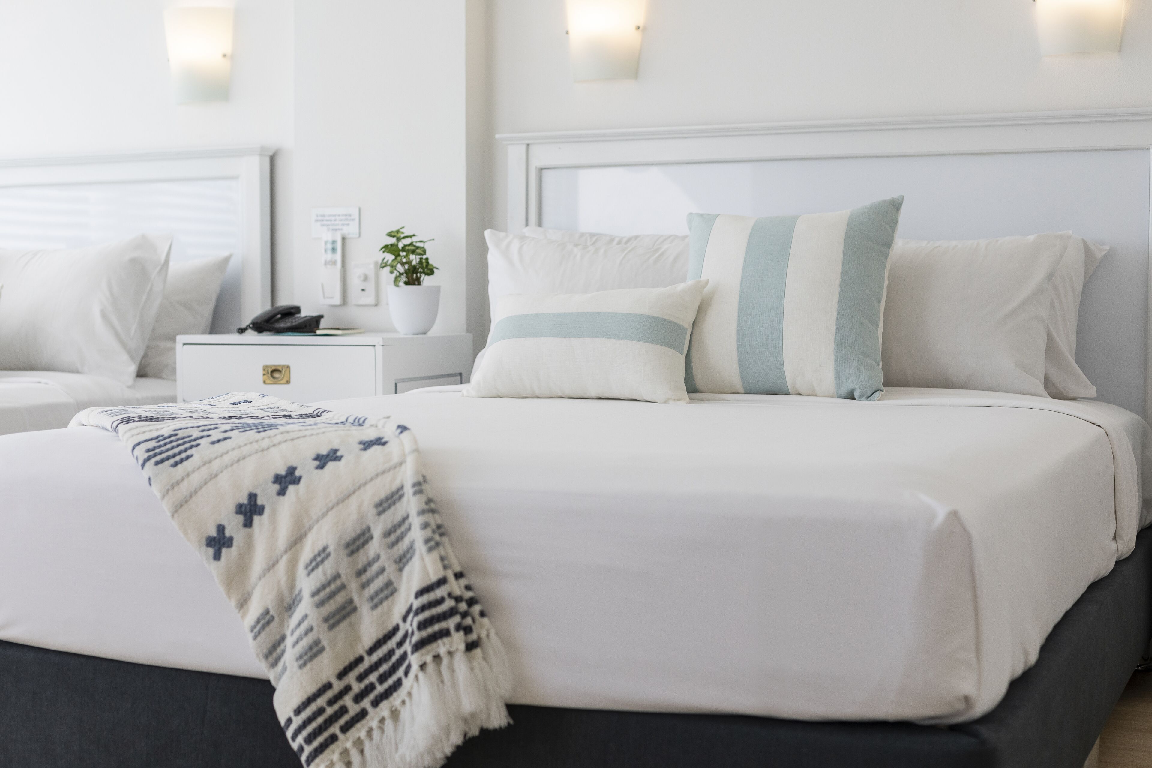 A neatly arranged bedroom with a bed, bedside tables, and a nightstand.