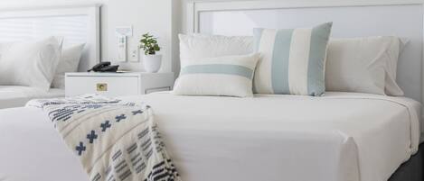 A neatly arranged bedroom with a bed, bedside tables, and a nightstand.