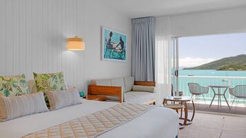 Habitación de hotel con una cama grande, un sofá, un balcón con vistas al mar y un cuadro en la pared.