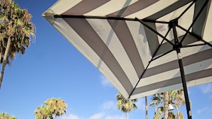 A pool area with lounge chairs, a table, and umbrellas providing shade.