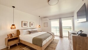 A bedroom with a bed, bedside tables, a desk, and a large window with a view.