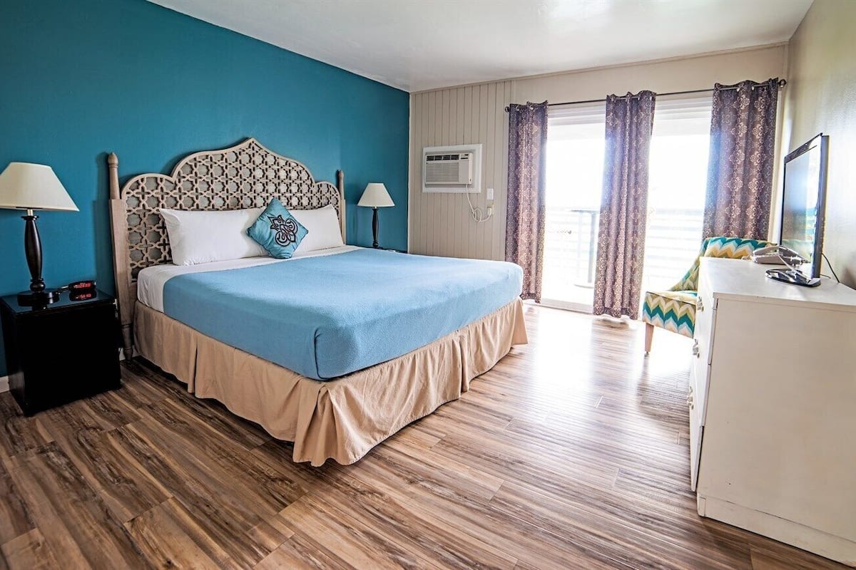 A bedroom with a bed, bedside tables, a desk, and a window with curtains.