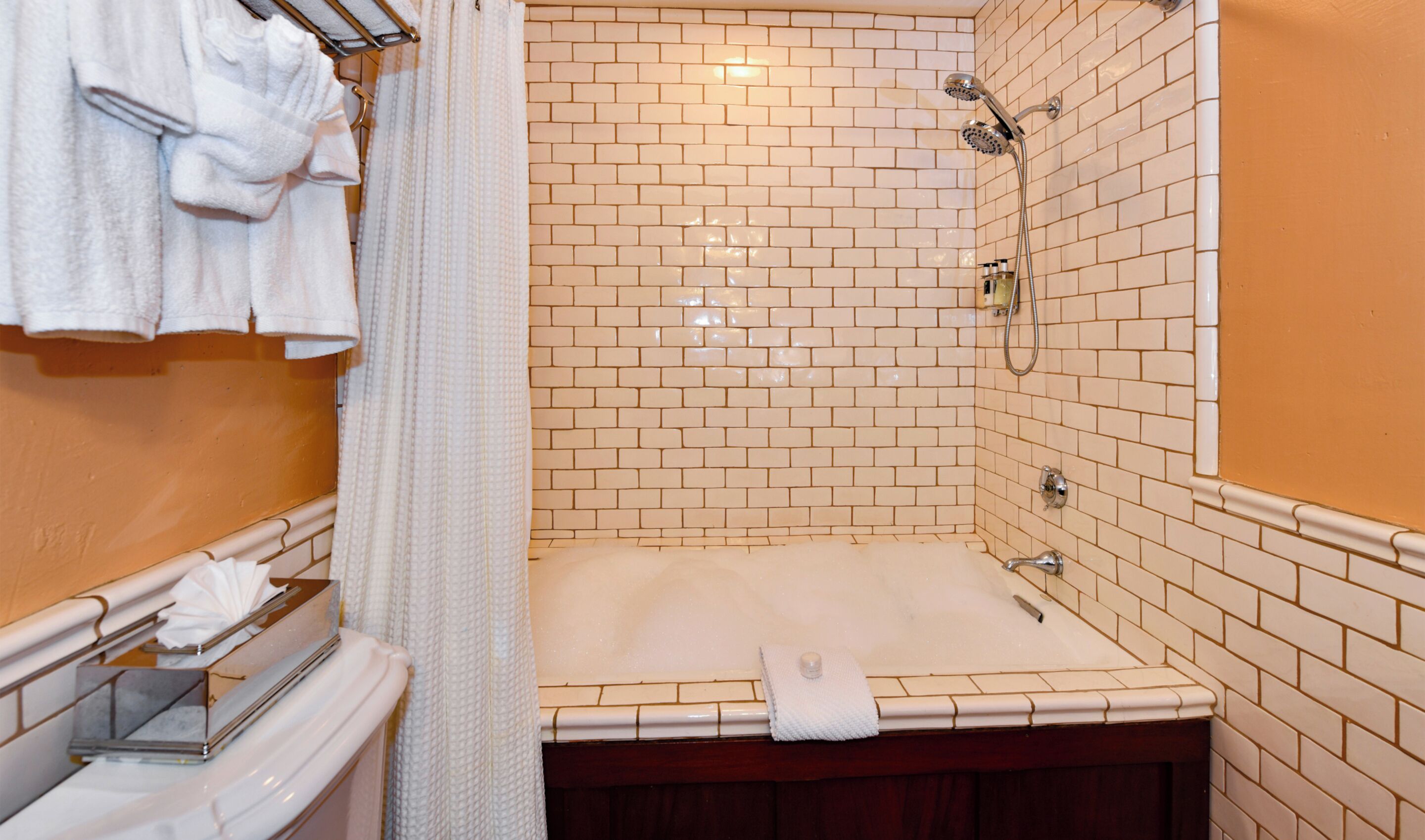 A bathroom with a bathtub, a shower, and a towel rack with towels.