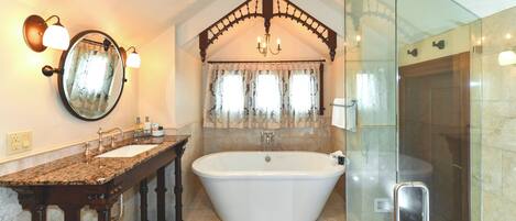 A bathroom with a freestanding bathtub, a glass-enclosed shower, and a vanity with a mirror and two sinks.