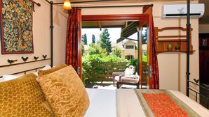 A bedroom with a bed, a window with red curtains, a view of the outside, and a wall-mounted air conditioner. - Blackbird Inn (Napa)