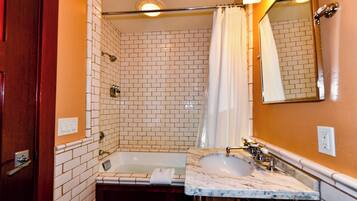 A bathroom with a white-tiled shower, a bathtub, and a marble sink.