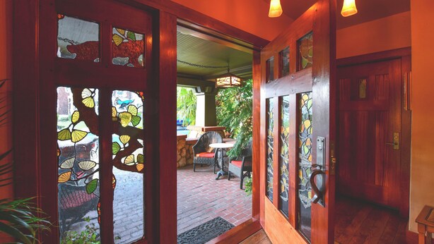 A wooden door with stained glass panels depicting leaves and birds. - Blackbird Inn (Napa)