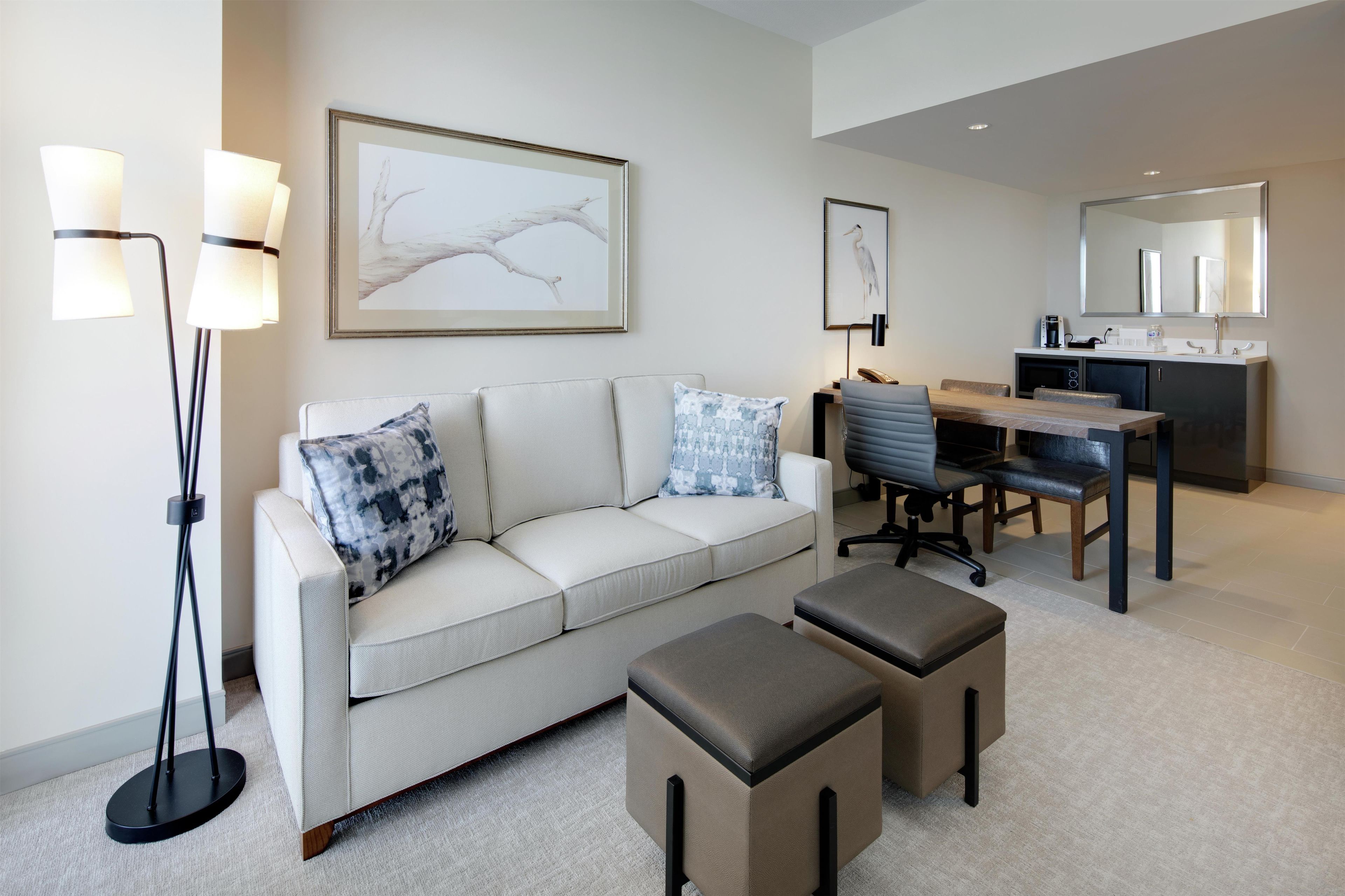 A modern living room with a sofa, a coffee table, a desk with a chair, and a large mirror.