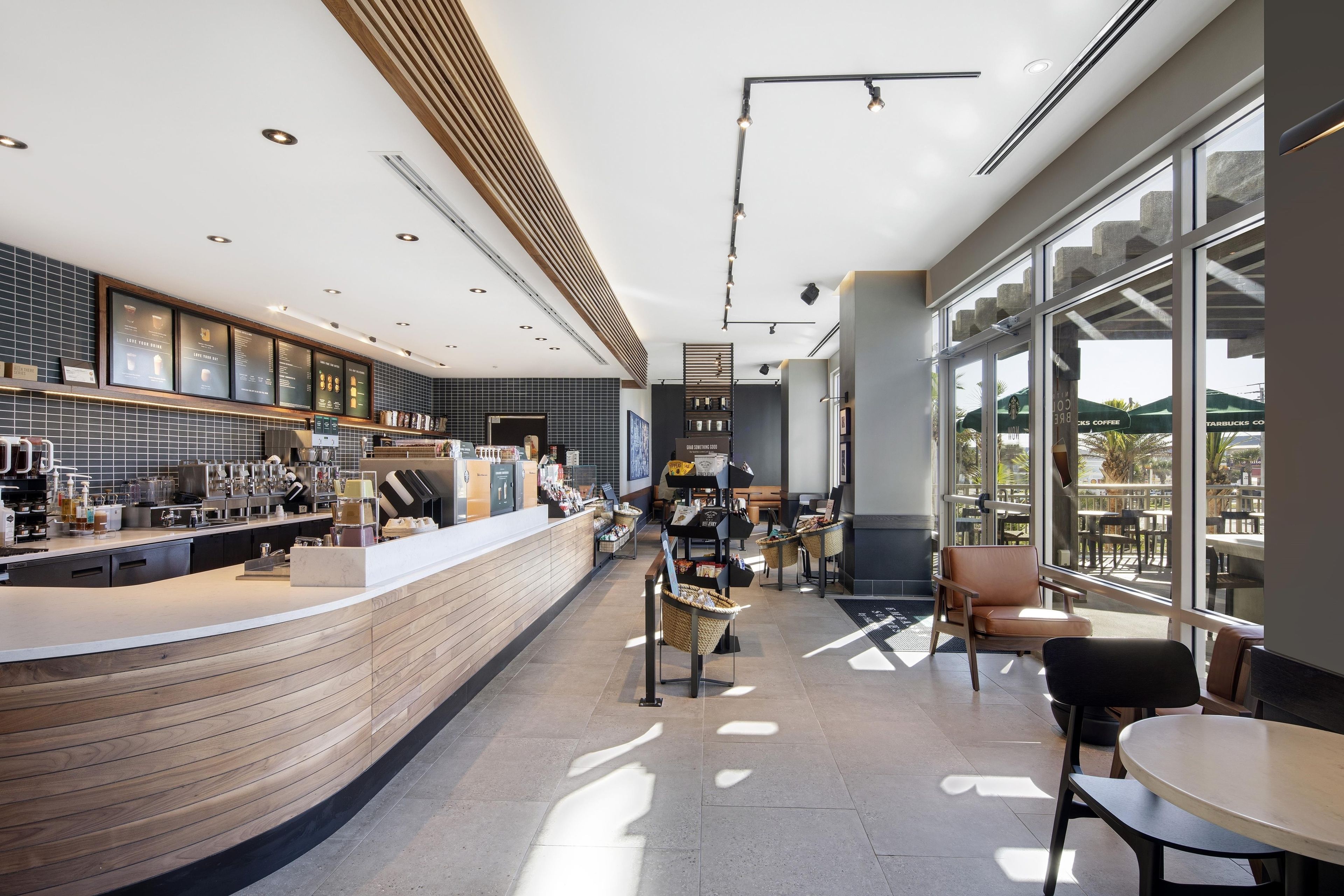 A modern coffee shop interior with a bar area, seating, and large windows.