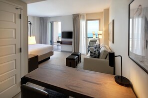Une chambre d’hôtel avec un lit, un bureau, une télévision et une vue sur la mer.