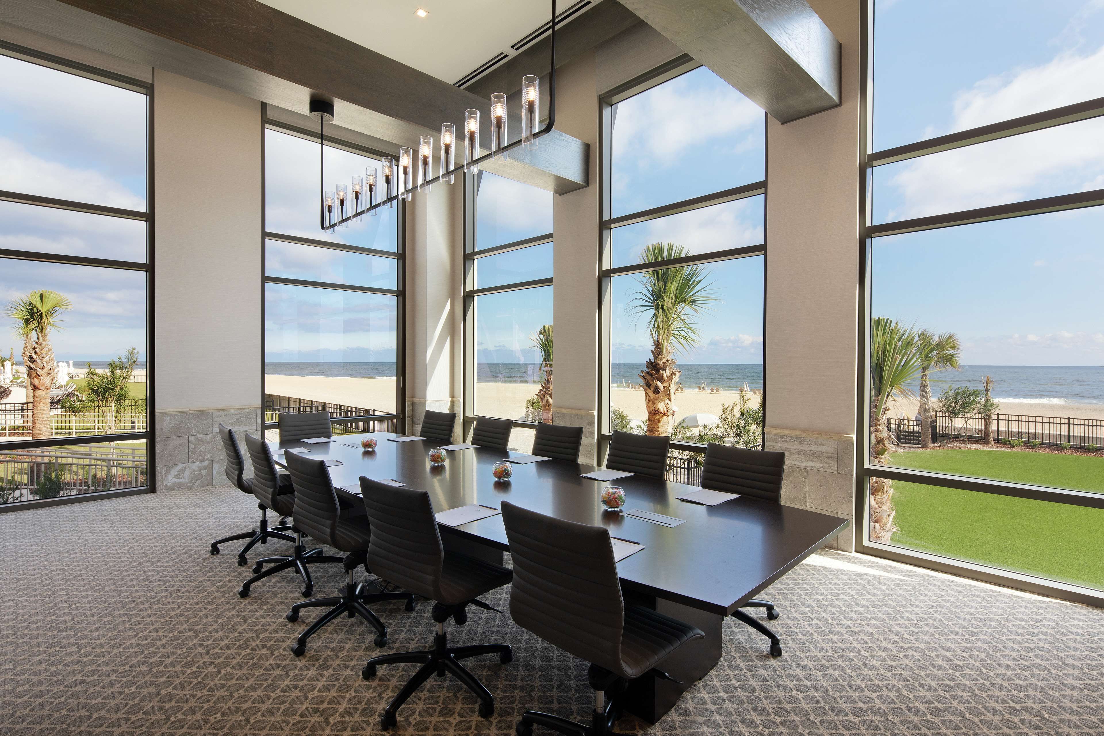 A conference room with a large table, chairs, and a view of the beach.