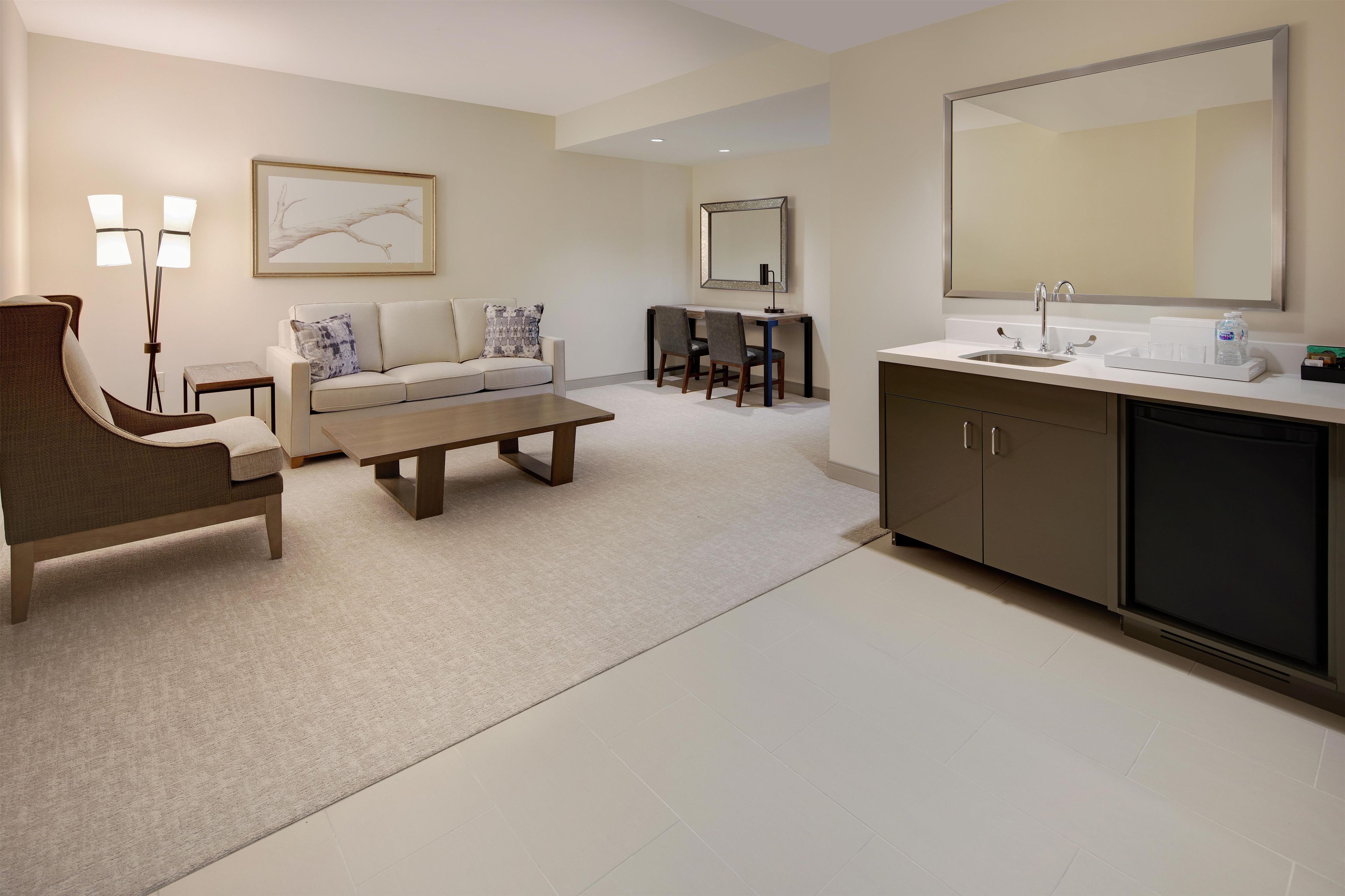 A modern living room with a sofa, coffee table, and a dining area with chairs.