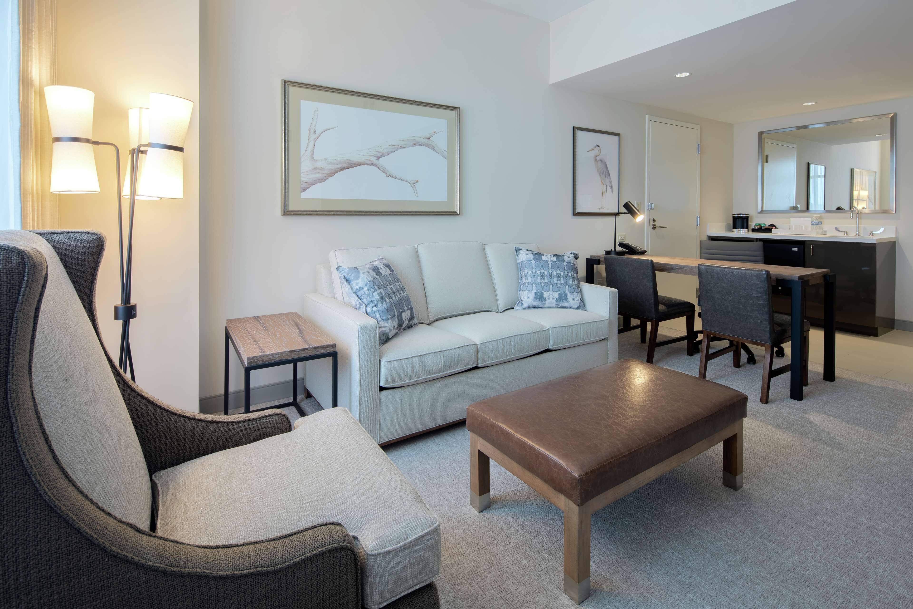 A modern living room with a sofa, armchair, coffee table, and dining area.