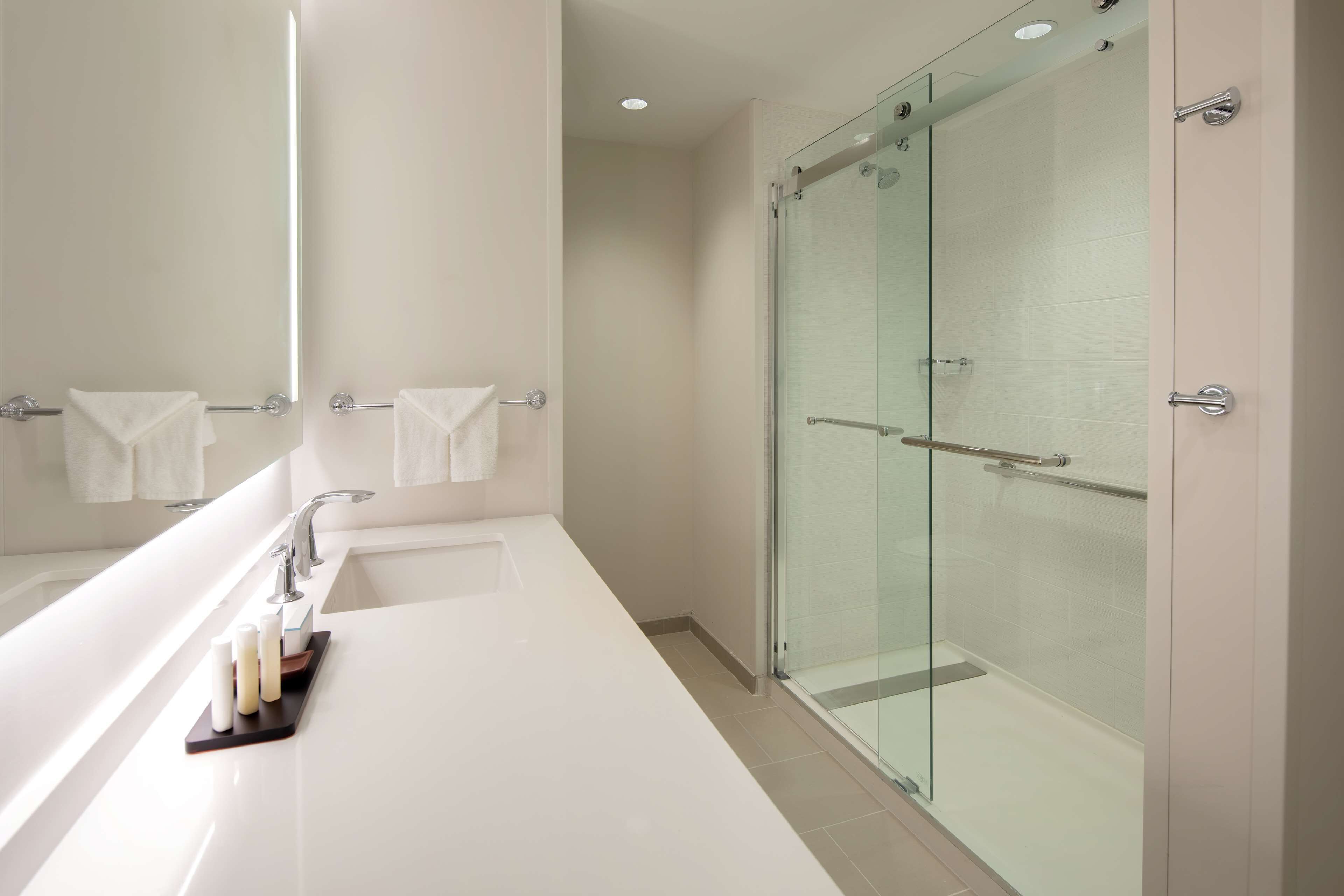 A modern bathroom with a large bathtub, a glass shower enclosure, and a mirror reflecting the room.