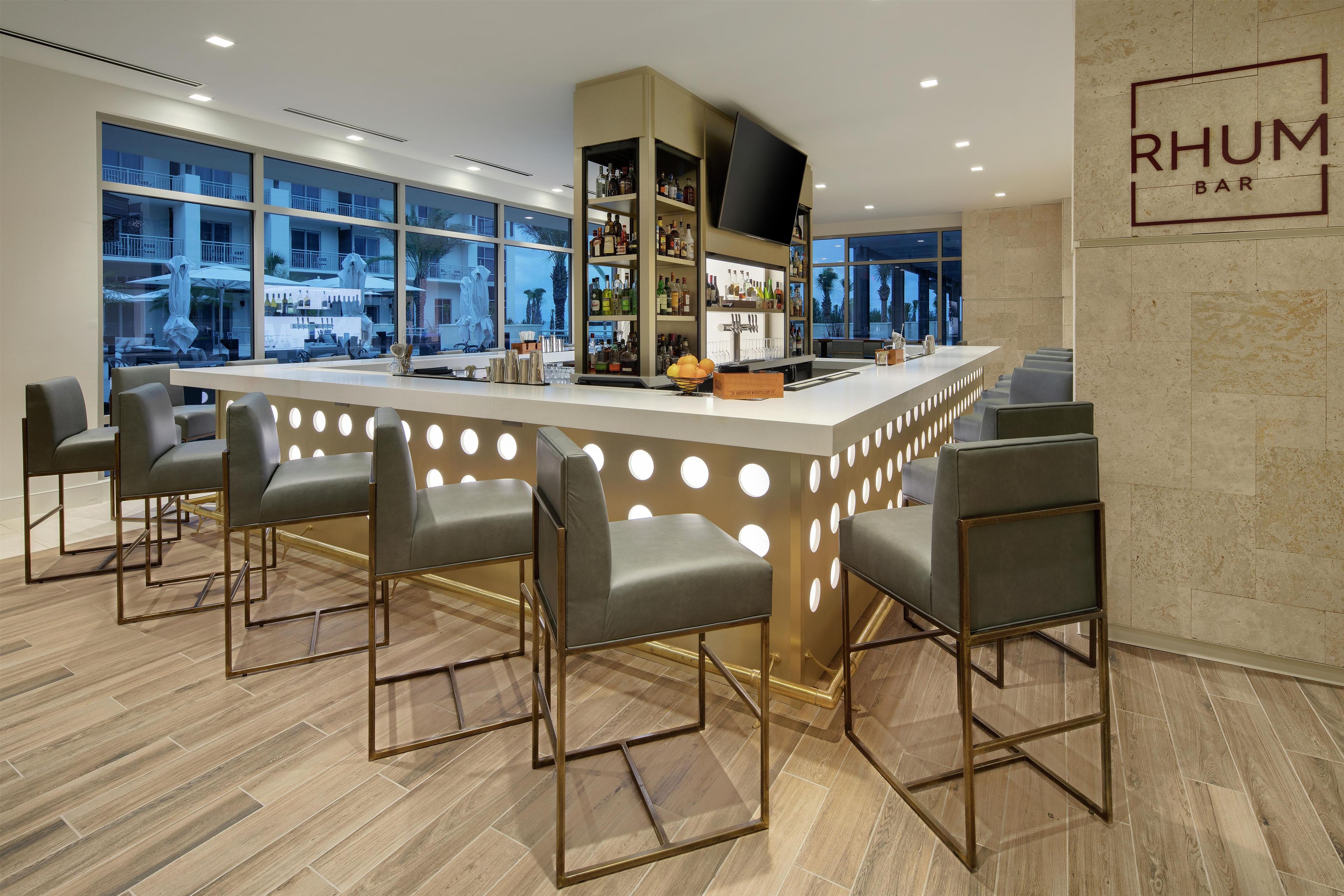 A bar area with a central island, bar stools, and a view of the outside through large windows.